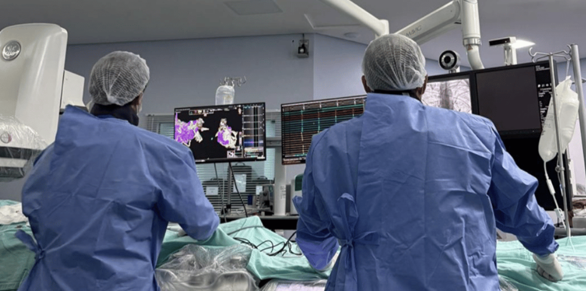 Equipe médica acompanha estudo eletrofisiológico em monitores na sala de hemodinâmica